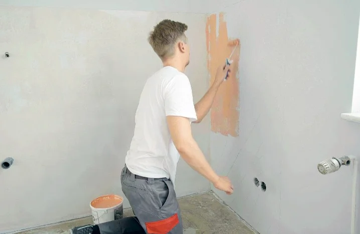 Person streicht Wand mit Farbrolle